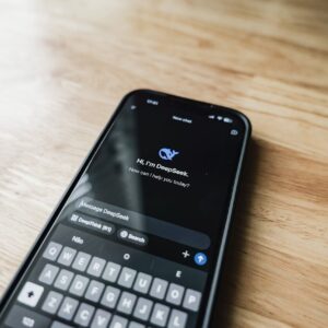 A smartphone displaying an AI chat interface, DeepSeek, on a wooden table.